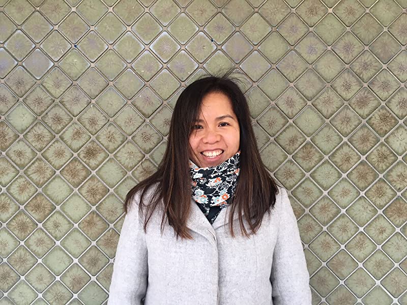 Picture of Children's Book Author and Illustrator Thao Lam. She is a Vietnamese Canadian woman, with long brown hair and sideswept bangs. She is wearing a scarf tucked into a seemingly very light gray coat. 