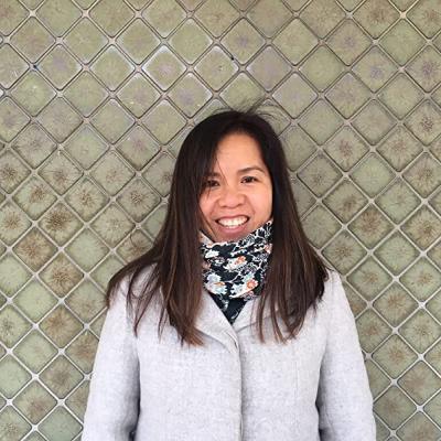 Picture of Children's Book Author and Illustrator Thao Lam. She is a Vietnamese Canadian woman, with long brown hair and sideswept bangs. She is wearing a scarf tucked into a seemingly very light gray coat. 