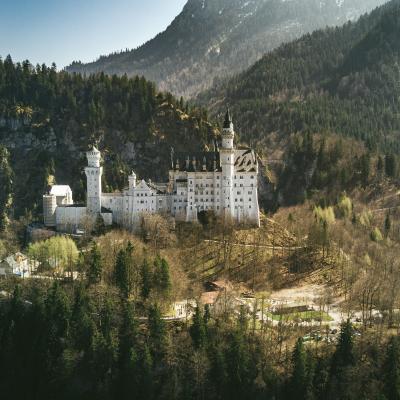 a white castle in the valley of mountains.