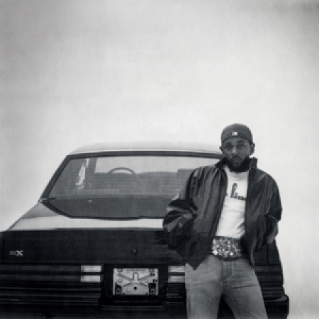 Kendrick Lamar leaning on Buick GNX